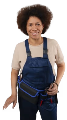 Smiling female plumber in blue denim overalls and a tool belt, holding a tool